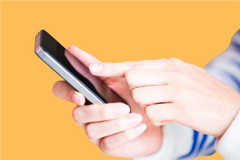 Mãos de uma pessoa digitando um número de telefone em um smartphone, ilustrando o processo de discagem para fazer uma ligação interurbana usando o código DDD e operadora.