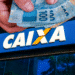 Depósito de R$ 200 da CAIXA: veja se você estará entre os contemplados nesta segunda‑feira 8 CAIXA: Mão segura notas de R$ 100 acima da logo. Ilustração do depósito de R$ 200, detalhando o calendário de pagamento e movimentação de valores para beneficiários.