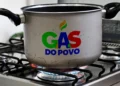 Panela simples sobre um fogão com a chama acesa, exibindo o logotipo "GÁS DO POVO" em cores vivas no centro da panela, para quem está cadastrado no CadÚnico.