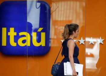 Trabalhe no Itaú: banco anuncia 81 vagas e inscrições já estão disponíveis 1 Mulher passando em frente a agência do Itaú, representando novas vagas de emprego disponíveis no banco.