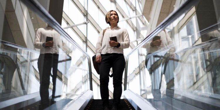 Carreiras promissoras no Brasil em 2026: salários, demanda e tendências 1 Jovem profissional em ascensão na escada rolante em prédio moderno de vidro, simbolizando o crescimento de carreira e novas oportunidades de trabalho em 2026.