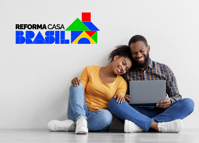 Casal sorridente sentado no chão, usando um laptop, com o logo colorido do programa Reforma Casa Brasil, representando o financiamento simplificado para reformas.