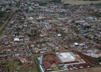 Vista aérea de uma cidade no Paraná com casas destruídas e telhados arrancados após um tornado, ilustrando o cenário de calamidade que permite o saque do FGTS.