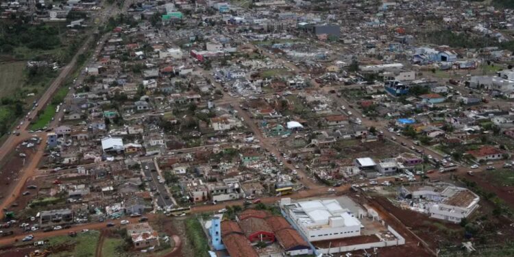 Vista aérea de uma cidade no Paraná com casas destruídas e telhados arrancados após um tornado, ilustrando o cenário de calamidade que permite o saque do FGTS.