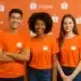Três pessoas sorrindo vestindo camisetas laranja da Shopee